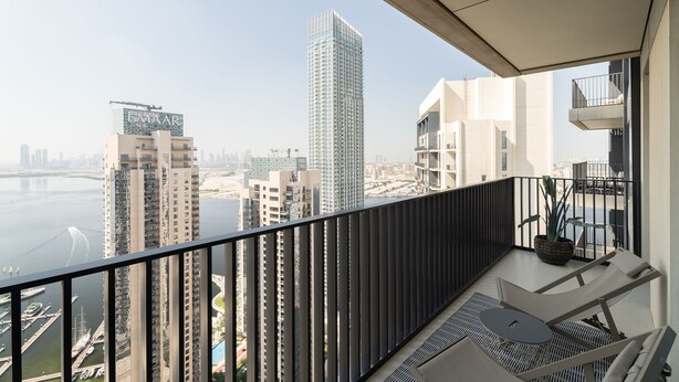 A balcony with a view of a cityscape, including high-rise buildings and a body of water. - Nasma Holiday Homes - Creek Horizon Tower 1 (Dubai)