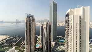 A high-rise building with a marina and a city skyline in the background. - Nasma Holiday Homes - Creek Horizon Tower 1 (Dubai)
