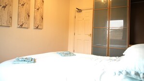 Ein Schlafzimmer mit einem Bett, einem Kleiderschrank und drei Bildern an der Wand.