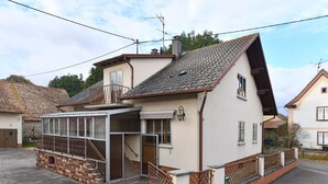 A two-story house with a balcony, a garage, and a small attached structure with a glass door. - Charming Home Between Colmar and Mulhouse, Near Wine Route and Europa-Park, Sleeps 6 (Oberentzen)
