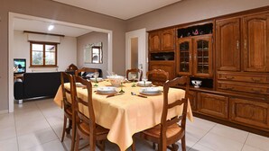 A dining area with a table set for four, wooden chairs, and a cabinet with glass doors. - Charming Home Between Colmar and Mulhouse, Near Wine Route and Europa-Park, Sleeps 6 (Oberentzen)