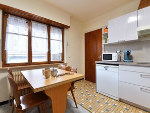 A small kitchen with a wooden table, chairs, a microwave, a coffee maker, and a dishwasher.