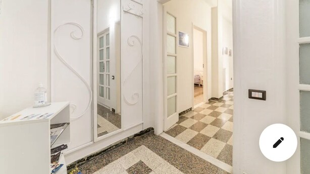 A hallway with a checkered floor, a white door, and a mirror with decorative swirls.