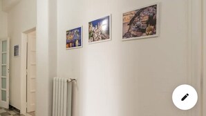 A hallway with three framed pictures on the wall, a radiator, and a door.