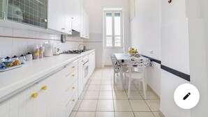 A compact kitchen with white cabinets, a gas stove, and a dining area with a table and chairs.