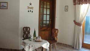 Un comedor con mesa de madera, sillas, una botella de vino y un pastel sobre un mantel.