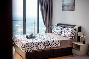 Une chambre avec un grand lit, une table de chevet, une fenêtre avec des rideaux et une vue sur le paysage urbain.