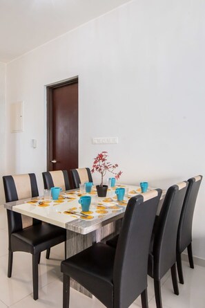 Un coin repas avec une table rectangulaire, des chaises noires et une plante en pot.