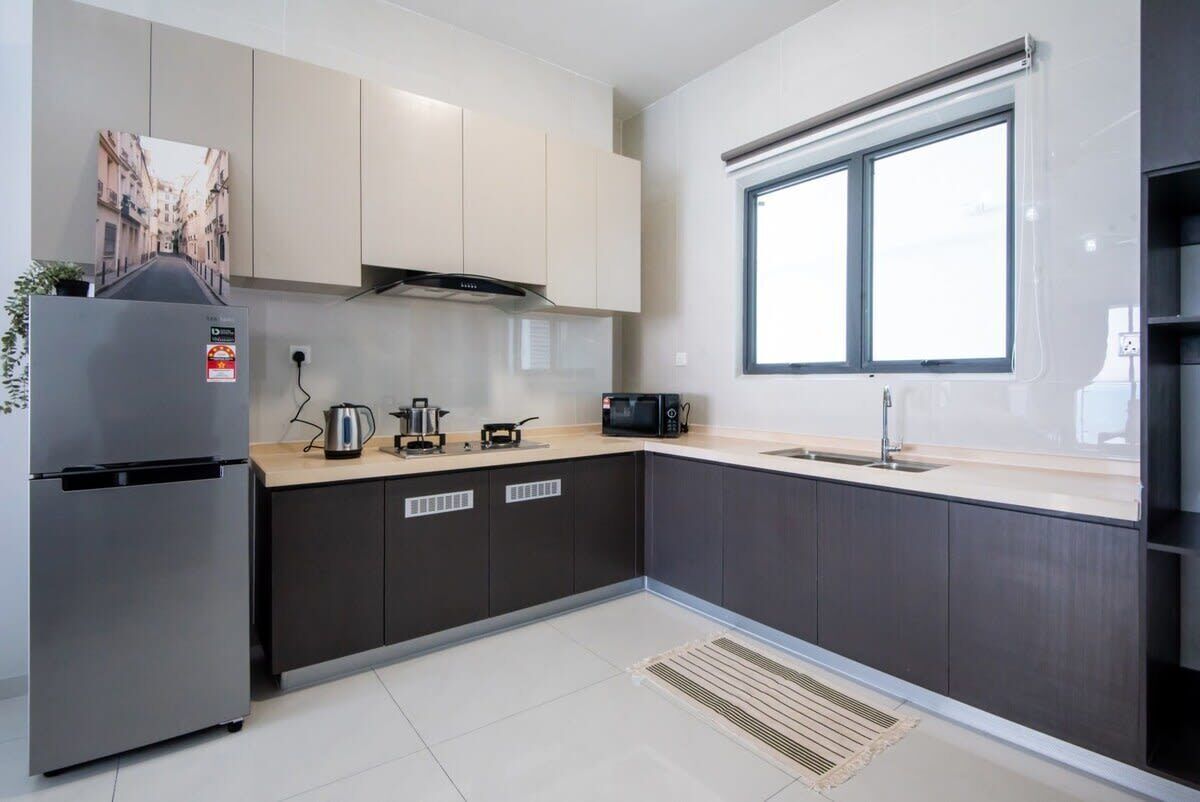 A modern kitchen with a stainless steel refrigerator, a microwave, a kettle, and a sink.