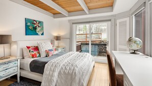 Een slaapkamer met een bed, een bureau met een wereldbol en uitzicht op een balkon.