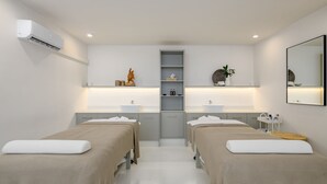 Una habitación de hotel moderna con dos camas, un lavamanos central y un espejo en la pared.
