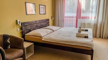 Ein ordentlich eingerichtetes Schlafzimmer mit einem hölzernen Bett, einem Stuhl und einem kleinen Nachttisch.