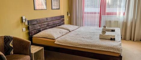 Un dormitorio ordenado con una cama de madera, una silla y una mesita de noche.