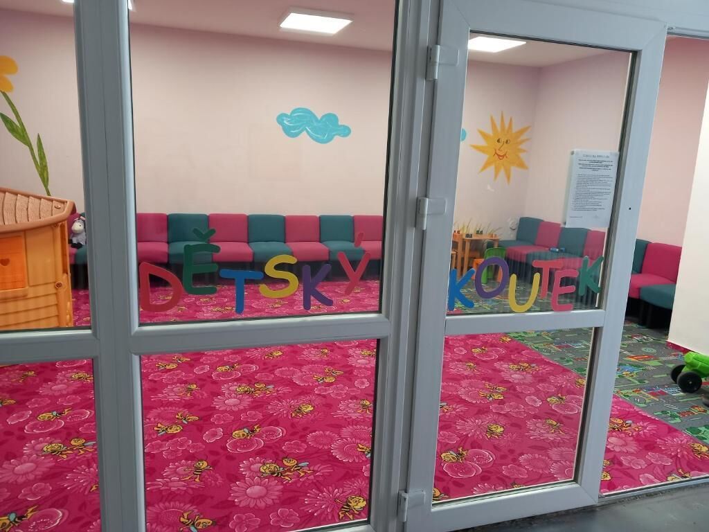 Una habitación con muebles coloridos, una alfombra floral y un muro con dibujos infantiles.