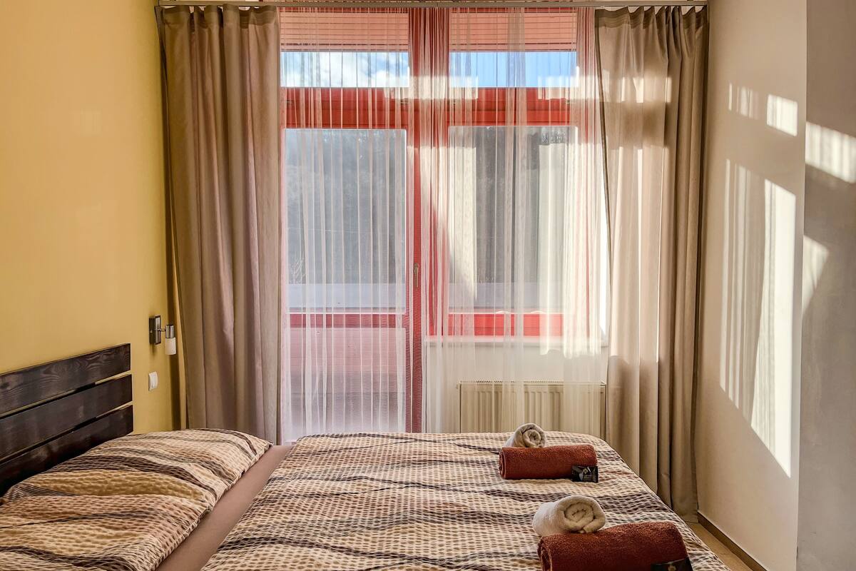 Una habitación de hotel con cama, cortinas, ventana y radiador.