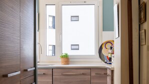 Eine moderne Küche mit Holzausstattung, einem Fenster mit Aussicht und einer kleinen Pflanze auf der Arbeitsfläche.