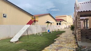 A residential area with a grassy lawn, a paved walkway, and a red slide. - Sea Wave Beach Resort (Kanthi)