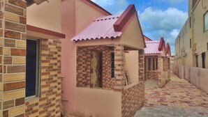 A row of buildings with brick facades and pink roofs, arranged along a narrow, paved walkway. - Sea Wave Beach Resort (Kanthi)