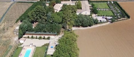 Vista aérea de una propiedad con piscina, varias edificaciones y campos aledaños.