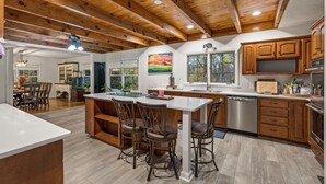 Una cocina amplia con armarios de madera, una isla central con taburetes y un gran ventanal que proporciona luz natural.