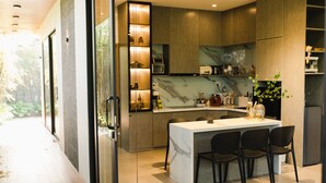 Una cocina moderna con encimera de mármol, electrodomésticos integrados y comedor con sillas negras.