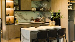 Una cocina moderna con encimera de mármol, electrodomésticos integrados y un comedor con isla de mármol y cuatro sillas.