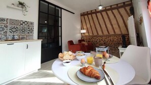 Ett modernt kök med en matplats, där en frukostservering med croissanter, ägg och juice dukas upp.