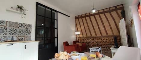 A modern kitchen with a dining area, featuring a breakfast setup with croissants, eggs, and juice.