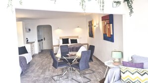 Een moderne woonkamer met een eettafel, stoelen, een bank en een keuken in de achtergrond.