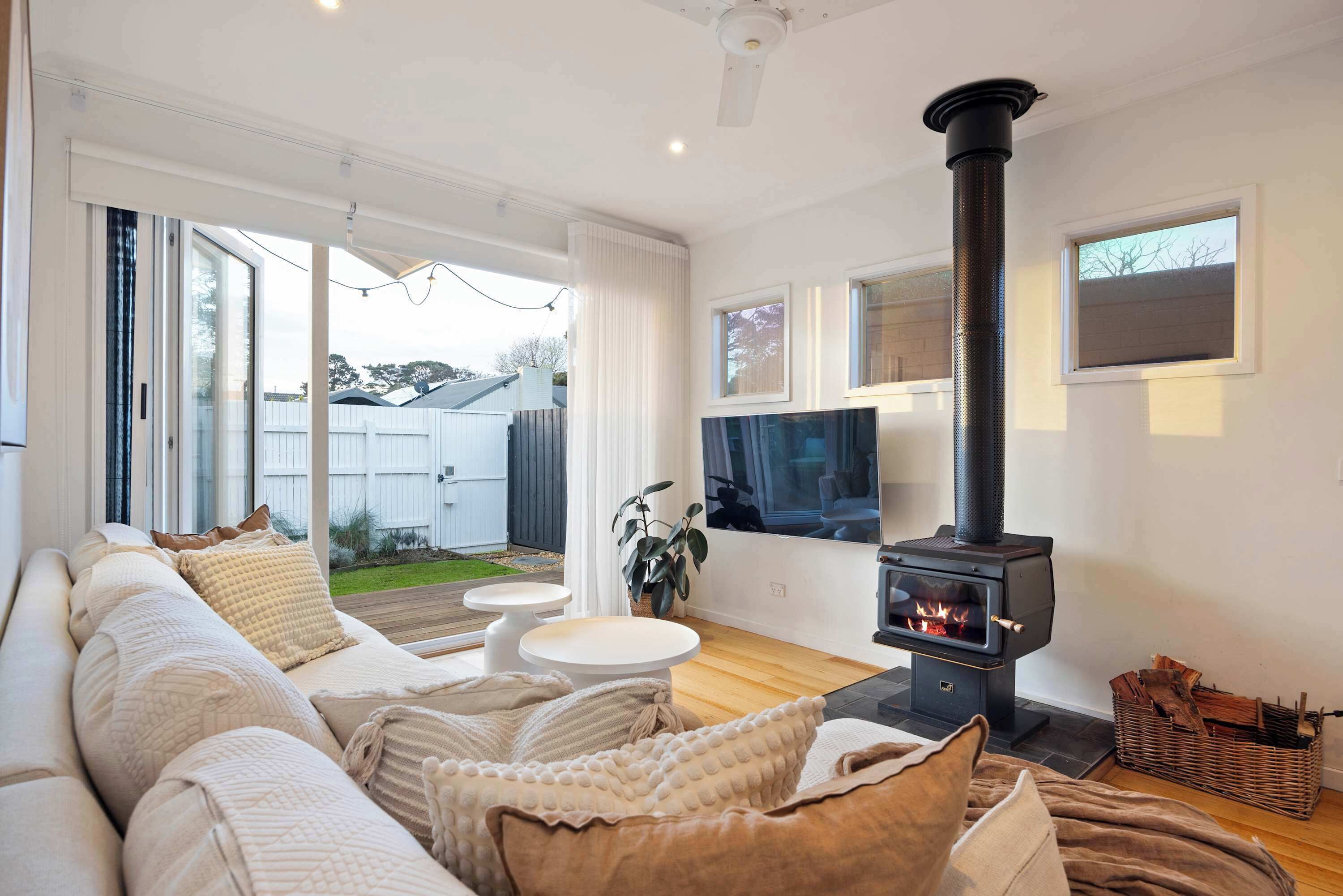 A living room with a sofa, a TV, a fireplace, and a view of the outdoors.