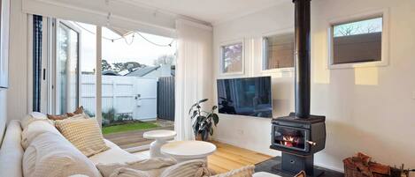 A living room with a sofa, a TV, a fireplace, and a view of the outdoors.