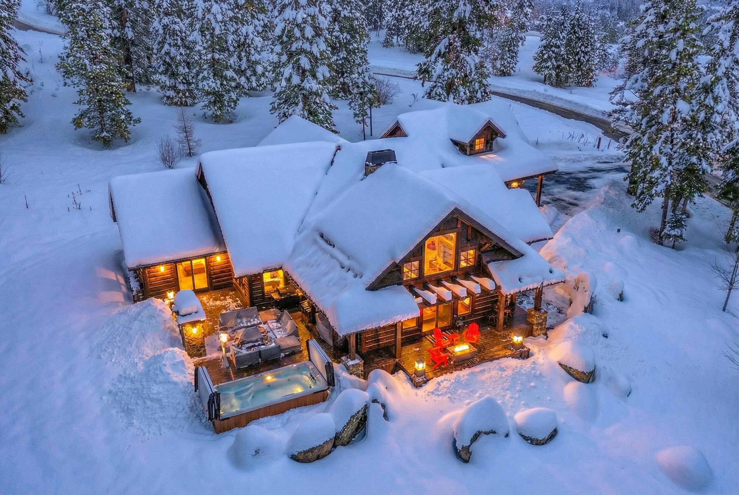 A snow-covered lodge with multiple rooms, a hot tub, and outdoor seating.