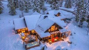 Una cabaña nevada con varias habitaciones, un jacuzzi y zona de estar exterior.