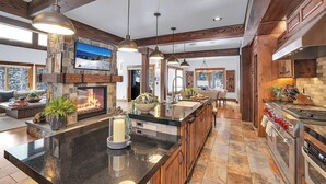 Una cocina amplia con una isla grande, vigas de madera y una chimenea de piedra.