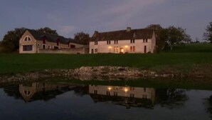A large, two-story house with a pond in front, surrounded by greenery. - La Domaine de Grandmont Evenements (Bonneuil-Matours)