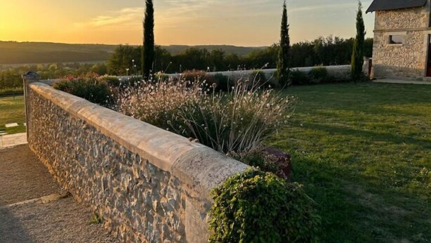 A stone wall with a garden, a grassy lawn, and a building with a stone facade. - La Domaine de Grandmont Evenements (Bonneuil-Matours)