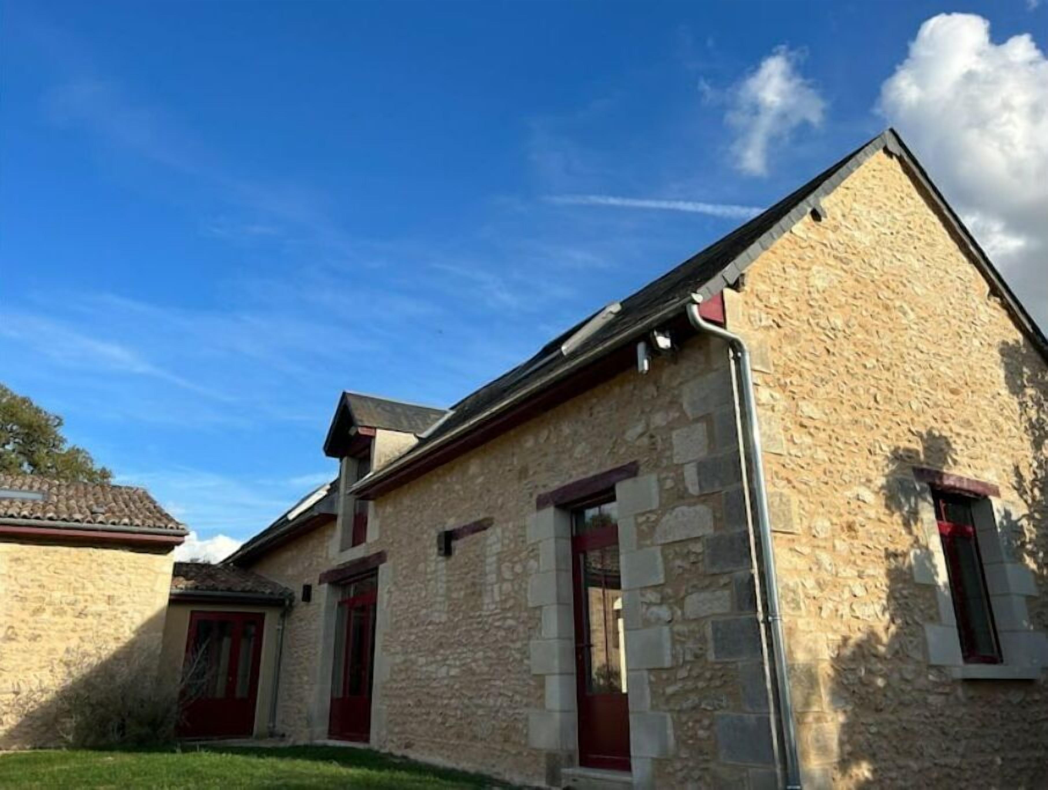 A stone building with a sloped roof, a visible chimney, and a small window.