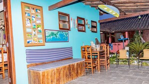 A cozy outdoor seating area with a wooden bench, wooden chairs, and a table. - Pousada Chalé do Beija-flor  (Ubatuba)