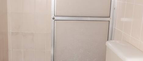 A bathroom with a white toilet, a shower area, and a tiled floor.