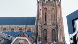 A historic church with a tall bell tower and a smaller adjacent building with a tiled roof. - This hotel is a 1 bedroom(s), 1 bathrooms, located in Delft, Zuid-Holland. (Delft)