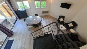 Un espace de vie compact comprenant un coin repas, un canapé et un escalier.