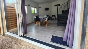 Une pièce spacieuse comprenant un coin repas, un escalier et une grande porte-fenêtre coulissante donnant sur l’extérieur.