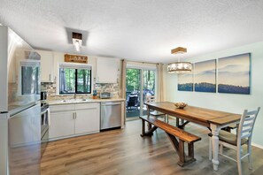 A modern kitchen with a dining area, wooden flooring, and a view of the outdoors. - Cozy Bear Lair - Arrowhead Lake (Pocono Lake)