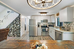 A modern kitchen with a central island, stainless steel appliances, and a decorative ceiling light. - Cozy Bear Lair - Arrowhead Lake (Pocono Lake)