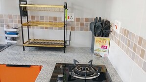 Keittiössä on musta liesi, hylly, jossa on astioita, ja laatikko pastaa.