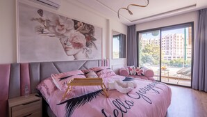 Ein Schlafzimmer mit einem großen Bett, einem Nachttisch, einer Wand-Klimaanlage und Blick ins Freie durch ein großes Fenster.