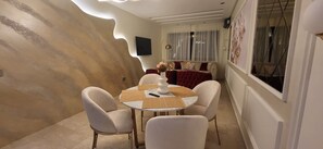 Un coin repas avec une table ronde, quatre chaises et un canapé en arrière-plan.