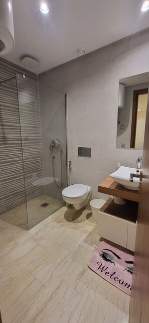 Une salle de bain moderne dotée d’une douche à parois de verre, de toilettes et d’un lavabo.