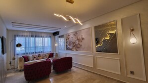 Ein modernes Wohnzimmer mit einer Couch, roten Sessel und einem großen Fenster, sowie Wanddekoration.