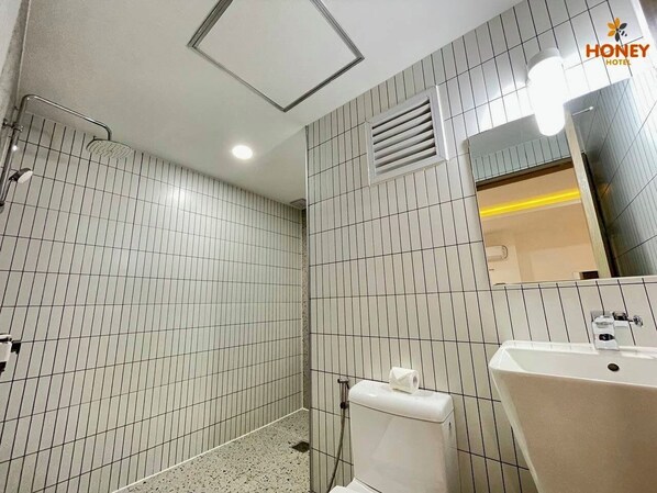 Une salle de bain avec douche, toilettes et lavabo.